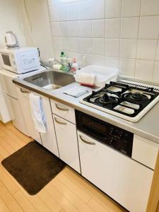 a white kitchen with a stove and a sink at Marvelous Kokubunji - Vacation STAY 80468v in Kokubunji