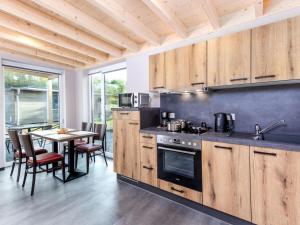 uma cozinha com armários de madeira e uma mesa com cadeiras em Tasteful bungalow in Hallschlag near the lakebeach em Hallschlag
