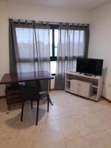 a living room with a table and a television at Dpto Piacentini in Resistencia +2 photos