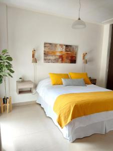 1 dormitorio con 1 cama con manta amarilla en Alberdi - Bon Repos en San Miguel de Tucumán