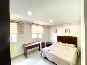 1 dormitorio con 1 cama, escritorio y ventanas en Acogedora casa muy cerca al centro histórico de Popayán en Popayán
