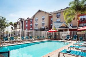 una piscina en un hotel con sillas y sombrillas en TownePlace Suites Los Angeles LAX Manhattan Beach, en Hawthorne