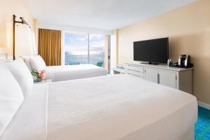 a hotel room with two beds and a flat screen tv at The Twin Fin Hotel in Honolulu