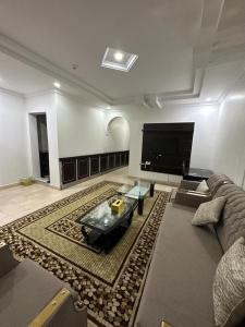 a living room with a couch and a large screen tv at شموع المروج للوحدات الفندقية in Tabuk