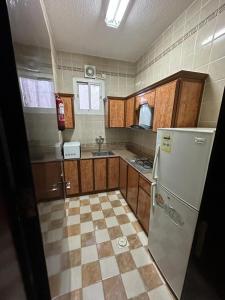 eine Küche mit Kühlschrank und Fliesenboden in der Unterkunft شموع المروج للوحدات الفندقية in Tabuk