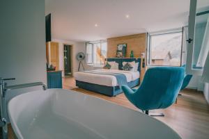 a bedroom with a bed and a blue chair and a tub at Terra-Beka Lodge in La Chapelle-dʼAbondance