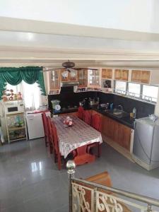a kitchen with a table with red chairs and a kitchen with at Triple N Homestay Beachfront House in Lobo in Lobo