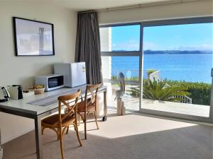 een keuken met een tafel en stoelen en uitzicht op de oceaan bij Once Upon a Tide in Auckland