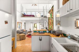 eine Küche mit weißen Schränken und ein Wohnzimmer in der Unterkunft Medina River Historic Cottage in Castroville