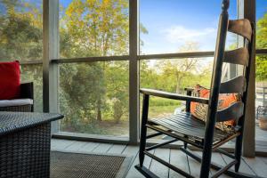 ein Schaukelstuhl auf der Veranda mit Blick auf die Bäume in der Unterkunft Medina River Historic Cottage in Castroville