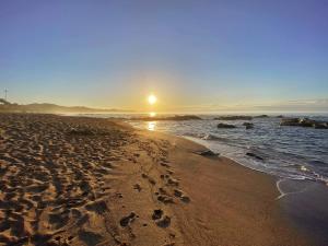 a beach with the sun rising over the ocean at Oasis Wadaura in Minamiboso