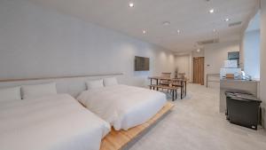a white bedroom with two beds and a table at Relax Hotel Takayama Station in Takayama
