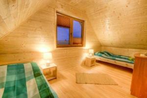 a log cabin bedroom with a bed and two windows at Ferienhaus in Mielno mit Grill in Mielenko