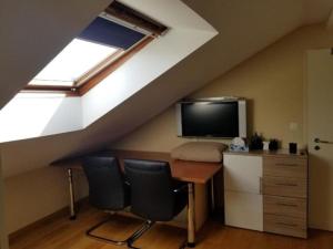 a room with a desk and a tv in a attic at Schönes Studio direkt am Bodensee in Altenrhein