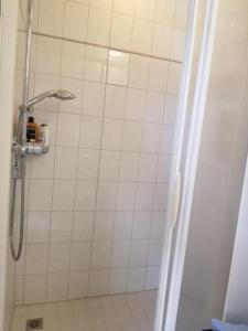 La salle de bains est pourvue d'une douche avec du carrelage blanc. dans l'établissement Schönes Studio direkt am Bodensee, à Altenrhein