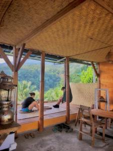 Eine Gruppe von Menschen sitzt auf einer Holzveranda mit Aussicht in der Unterkunft Rinjani Houseboon in Senaru