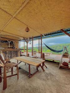 um quarto amplo com uma mesa de madeira e uma rede de descanso em Rinjani Houseboon em Senaru