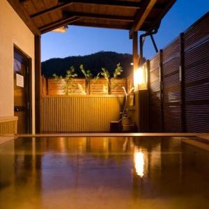 a room with a swimming pool with a view of a house at Hotel Kameya Honten in Chikuma