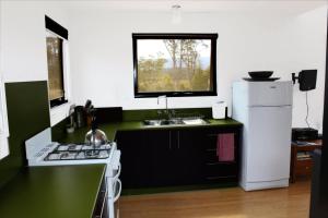 eine Küche mit Spüle und einem weißen Kühlschrank in der Unterkunft Far South Eco-Cabin, Southern Tasmania in Lune River
