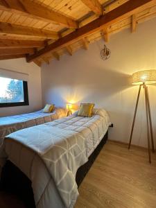two beds in a room with wooden ceilings at Espino Blanco Apartamentos in San Carlos de Bariloche