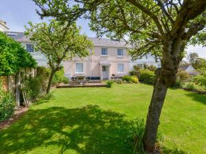 una gran casa blanca con un patio con árboles en 4 Coastguards Cottage, en Hope-Cove