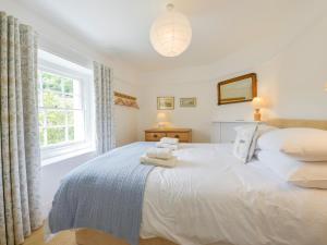 Un dormitorio con una cama blanca con toallas. en 4 Coastguards Cottage, en Hope-Cove