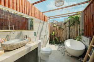 a bathroom with a sink and a toilet and a tub at Eco LoveBamboo in Dalung