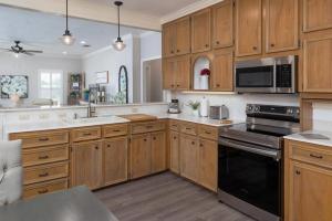 a kitchen with wooden cabinets and a stove top oven at NEW! Dragonfly at Firefly Grove w/ River Access in Wimberley
