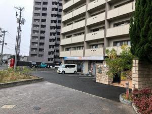 una furgoneta blanca estacionada en un estacionamiento frente a un edificio en Alphabed Fukuyama Nishi Sakura Machi 205 / Vacation STAY 22290 en Fukuyama