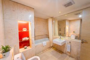 a bathroom with a tub and a sink and a toilet at Grand Jatra Hotel Balikpapan in Balikpapan