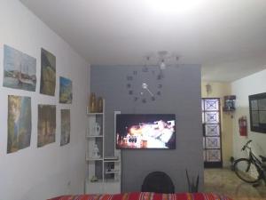 uma sala de estar com um relógio e uma televisão na parede em Chakana Family Home Lima Airport em Lima