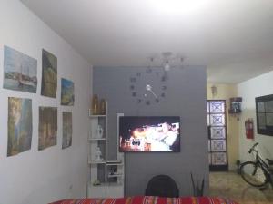 sala de estar con reloj y TV en la pared en Chakana Family Home Lima Airport, en Lima