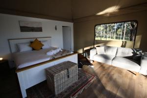 a bedroom with a bed and a couch and a chair at Two Fat Blokes Outback Adventure Glamping in Pokolbin