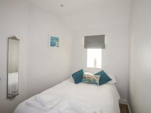 - une chambre avec un lit blanc et des oreillers bleus dans l'établissement Tyn Towyn - Bwthyn Carreg, à Trearddur