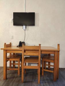 une table en bois avec une télévision murale dans l'établissement Kings Court Motor Lodge, à Hamilton