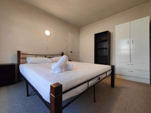 - une chambre avec un grand lit et des draps blancs dans l'établissement Kings Court Motor Lodge, à Hamilton