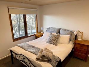 a bedroom with a bed with pillows and a window at Rainbow B in Falls Creek