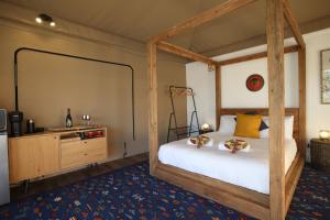 - une chambre avec un lit à baldaquin et une commode dans l'établissement Two Fat Blokes African Safari Glamping, à Pokolbin