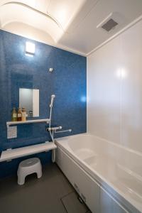La salle de bains est pourvue d'une baignoire blanche et d'un mur bleu. dans l'établissement こてーじDo, à Nagura