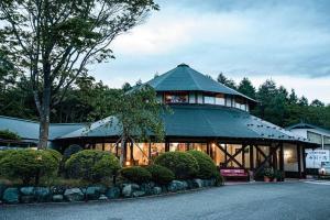 a large building with a green roof with bushes at 4月リニューアルOpen! 全室エアコン完備! Deerview Lodge 山中湖 in Yamanakako