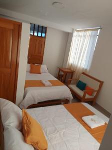 a hotel room with two beds and a chair at Majestic Mical in Yurimaguas