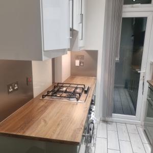 a kitchen with white cabinets and a wooden counter top at double room in Thornton Heath