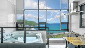 a bath tub in a room with a large window at Jini Spa Pension B in Geoje 