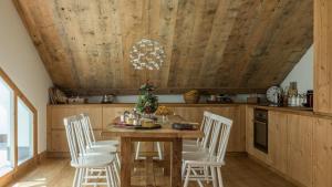 uma cozinha com um tecto de madeira e uma mesa e cadeiras de madeira em Ches'Ota - Verde - La Punt em La Punt-Chamues-ch