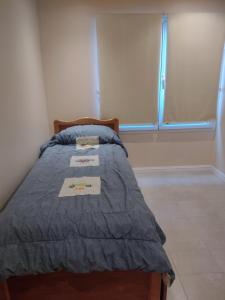 1 dormitorio con 1 cama con edredón azul y ventana en Sueños de Montaña en Esquel