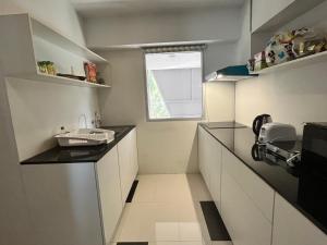 una pequeña cocina con armarios blancos y una ventana en Replay Residences Samui, en Bangrak Beach