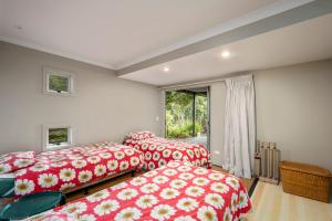 2 camas en una habitación con sábanas rojas y blancas en Five Mile Bliss - Lake Taupo Holiday Home, en Waitahanui
