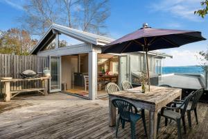 a table and chairs with an umbrella on a deck at Five Mile Bliss - Lake Taupo Holiday Home in Waitahanui
