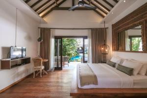 a bedroom with a bed and a tv and a patio at Villa Aram Canggu in Canggu