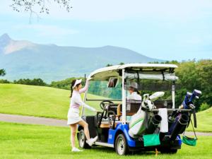 Una mujer está parada junto a un carrito de golf. en Hakodate-Onuma Prince Hotel, en Nanae